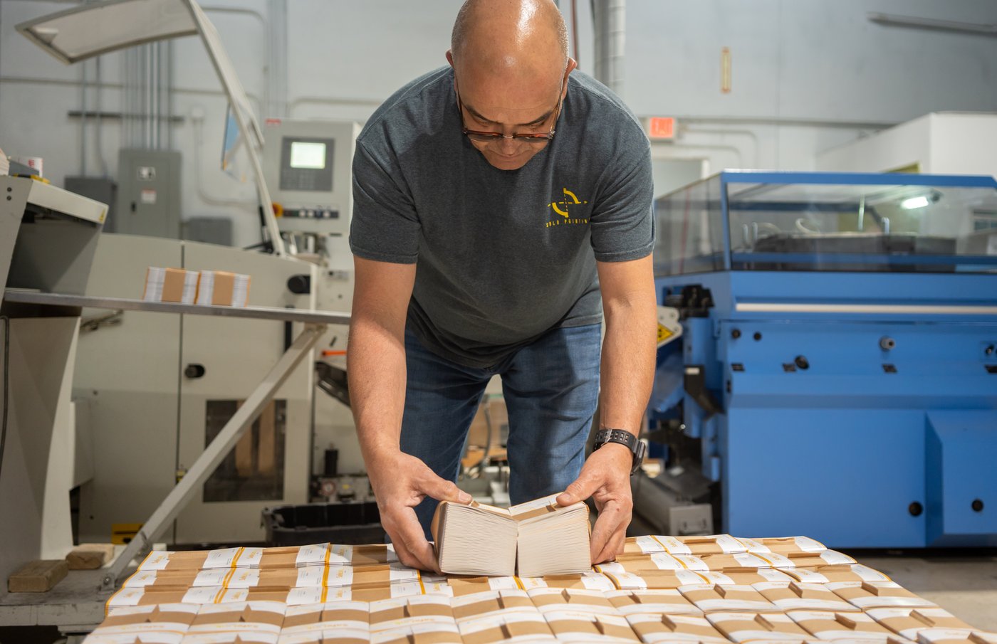 Solo Printing operator inspecting finished booklets in the bindery in Miami