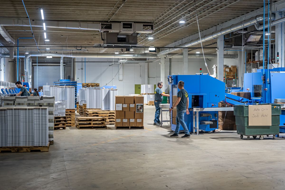 Wide view of the Solo Printing production floor with presses, bindery, and pallets of printed work in Miami